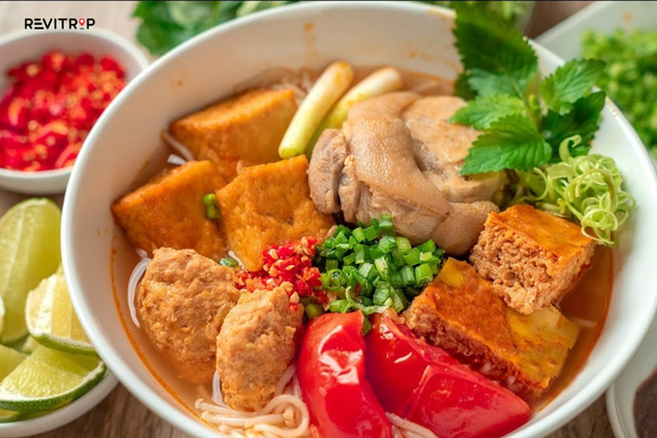 Bun rieu is a noodle soup built around a tomato-red broth fragrant with field crab paste and a gentle sourness