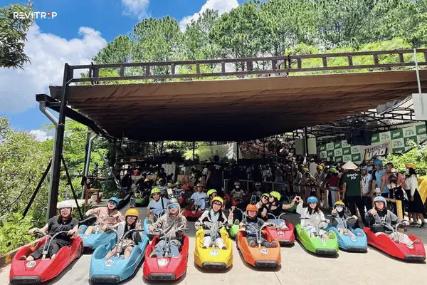 Visitors sitting in small wheeled carts before riding downhill in Da Lat