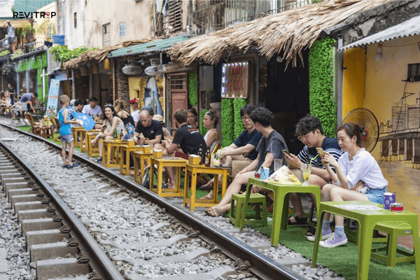 Hanoi Train Street cafe with plastic chairs beside the train tracks and tourists waiting for the train